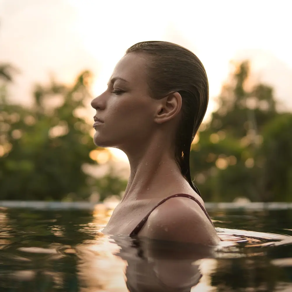 Girl in the pool on a sunset background f5ll5h7